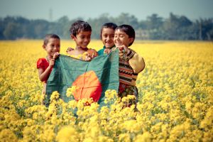 Bangladeshi children playing in a field of mustard shrubs.
